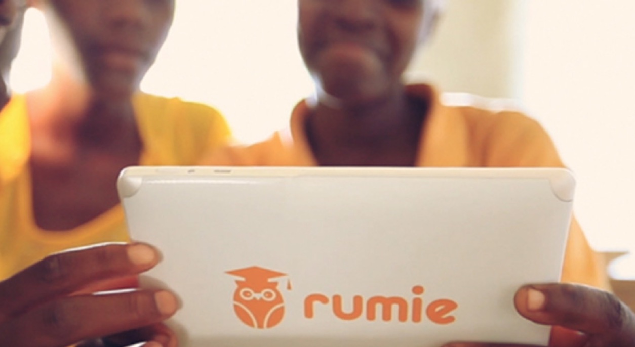 Two children looking at a computer tablet with Rumie logo